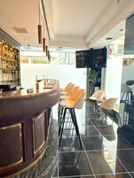 Un área de bar moderna con una barra curva, taburetes y un televisor montado en la pared.