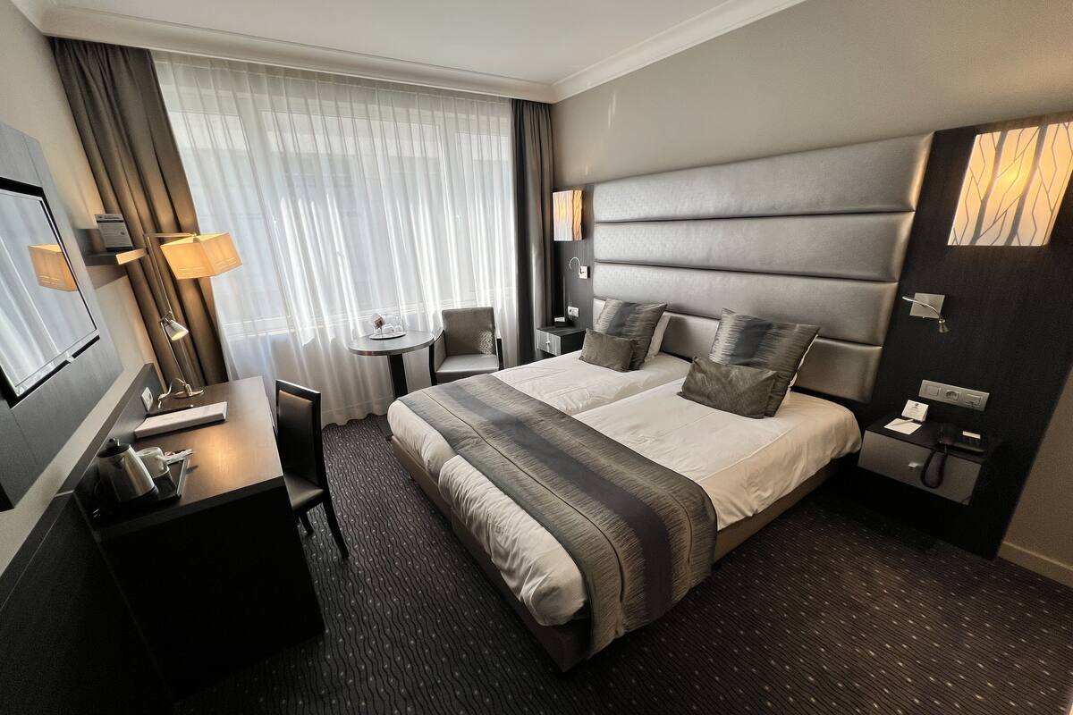 Una habitación de hotel moderna con una cama grande, mesitas de noche, un escritorio y una silla.