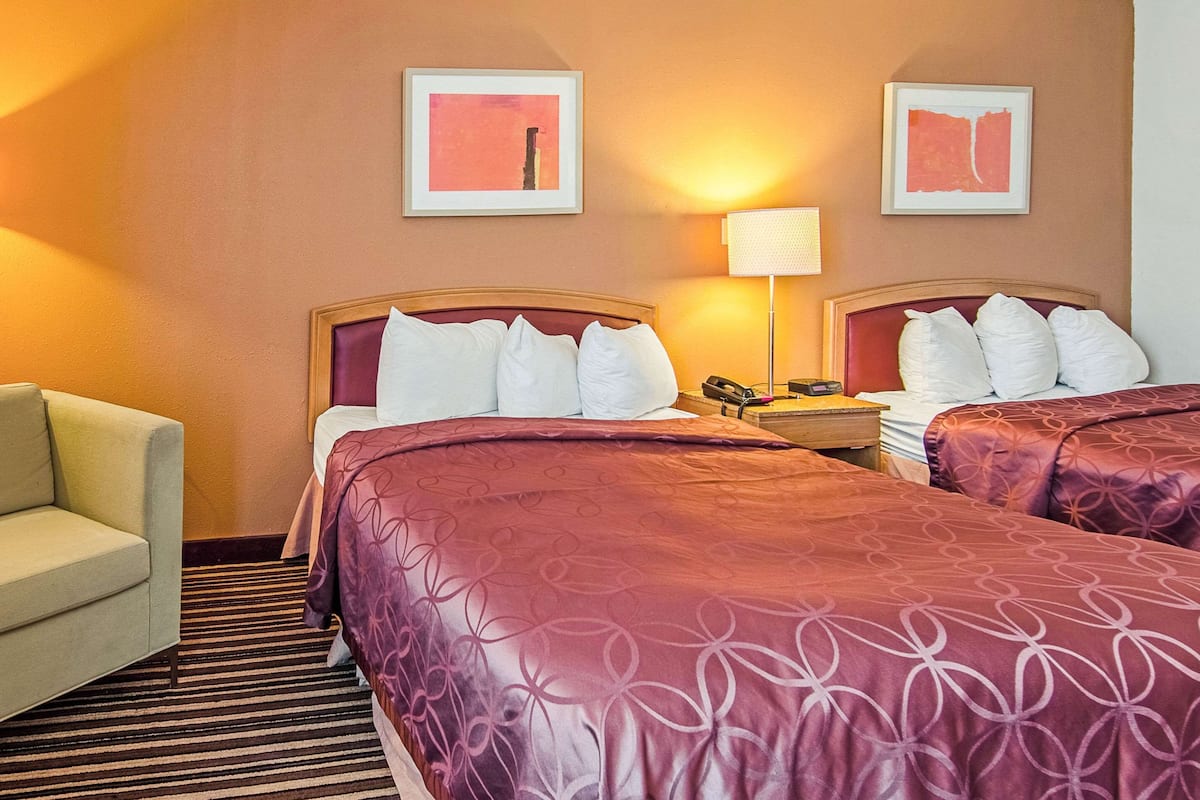 A hotel room with two beds, a sofa, and two framed pictures on the wall.