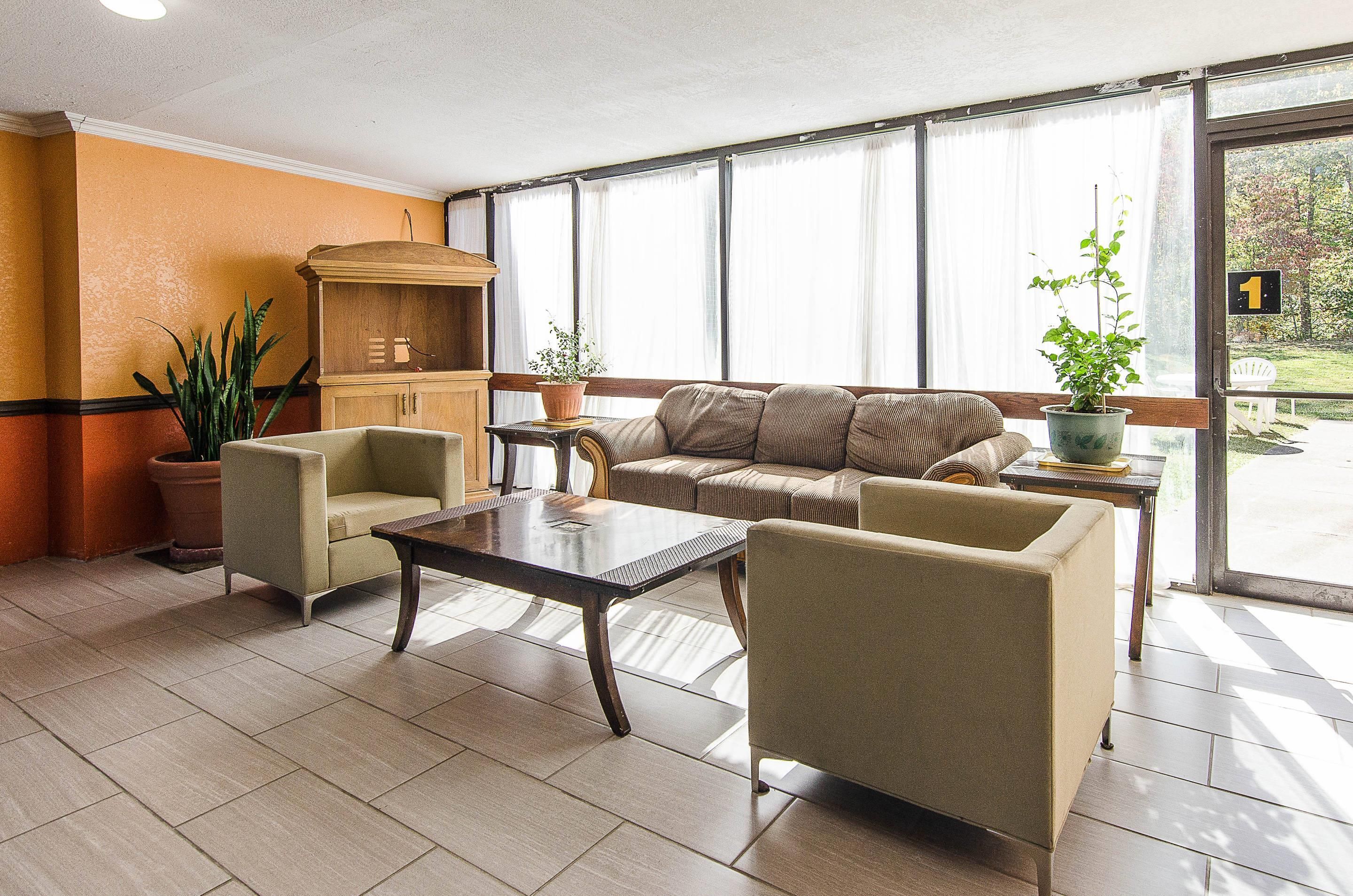 Un hall d’entrée comprenant un canapé, des fauteuils, une table basse, un meuble et des plantes en pot.