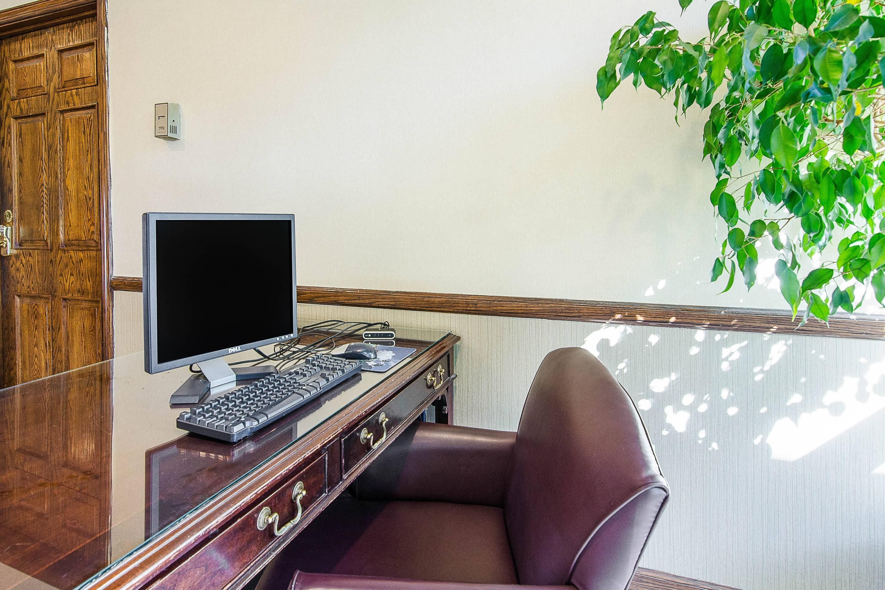 Un bureau en bois avec un ordinateur, un clavier et une souris. Une chaise est placée devant le bureau.