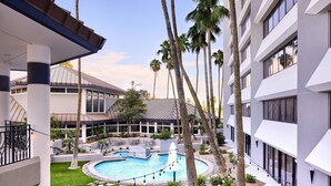 A hotel courtyard with a swimming pool, palm trees, and a covered seating area. - Delta Hotels by Marriott Phoenix Mesa (Mesa)