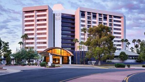 A modern hotel with a prominent entrance, multiple floors, and a clear sky. - Delta Hotels by Marriott Phoenix Mesa (Mesa)
