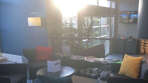 A modern lobby with comfortable seating, a flat-screen TV, and a large window offering a view of the outside.