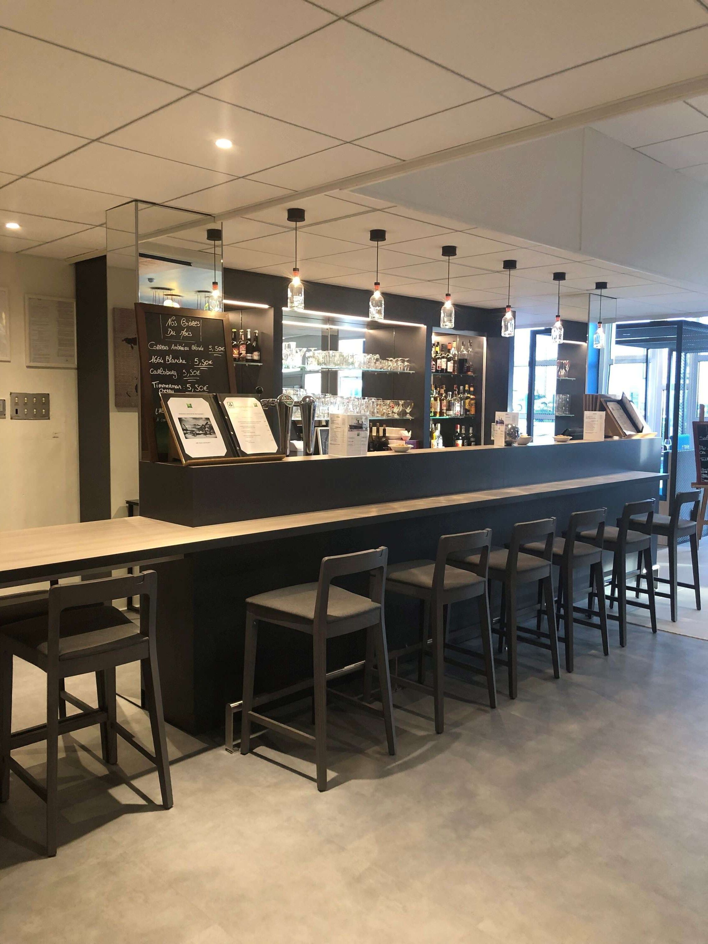A modern bar area with a counter, bar stools, and hanging pendant lights.