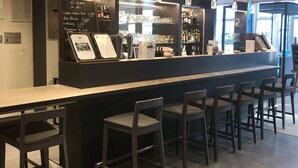 A modern bar area with a counter, bar stools, and hanging pendant lights. - ibis Styles Beauvais (Beauvais)
