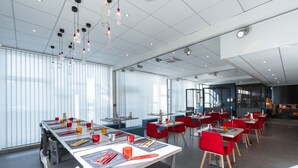 Un espace de restauration moderne, doté de tables et de chaises, de grandes fenêtres et de luminaires suspendus.