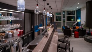Un espace bar moderne avec des luminaires suspendus, un long comptoir et des sièges disposés de manière conviviale.