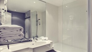 A modern bathroom with a glass shower enclosure, a sink with a towel rack, and a mirror. - ibis Styles Beauvais (Beauvais)