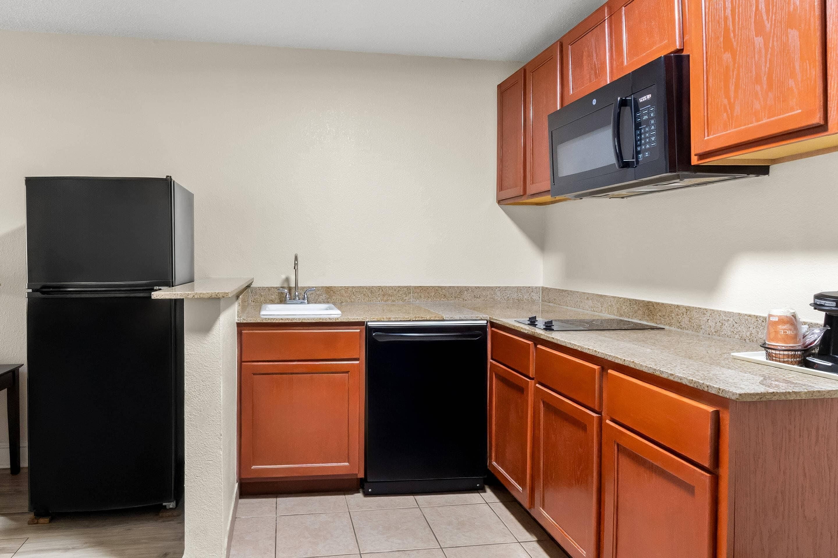 A compact kitchen with a refrigerator, dishwasher, microwave, and wooden cabinets.