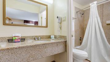 A bathroom with a granite countertop, a white sink, a mirror, a hairdryer, and a shower curtain.