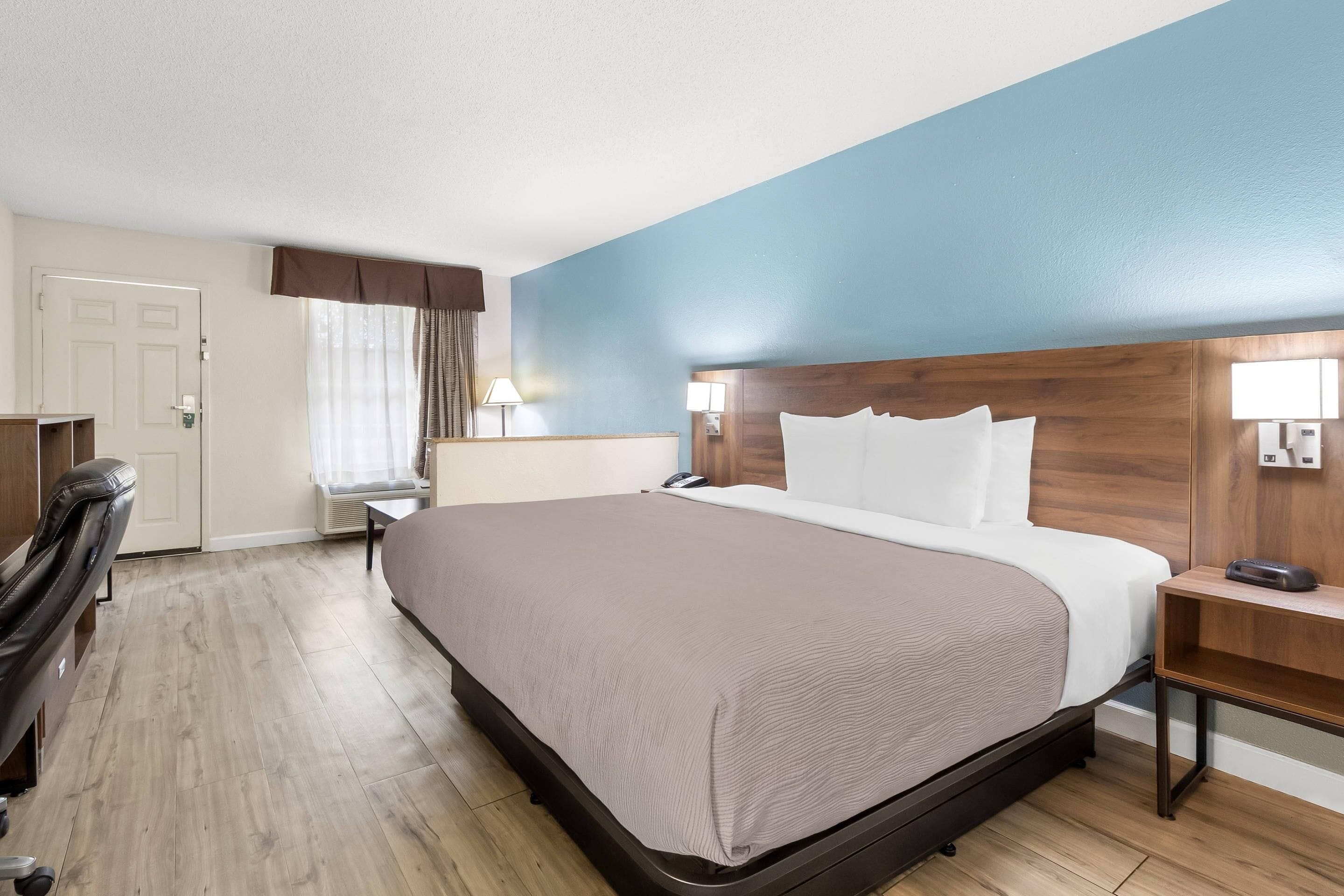 Ein Hotelzimmer mit Bett, Schreibtisch, Stuhl und Kleiderschrank.