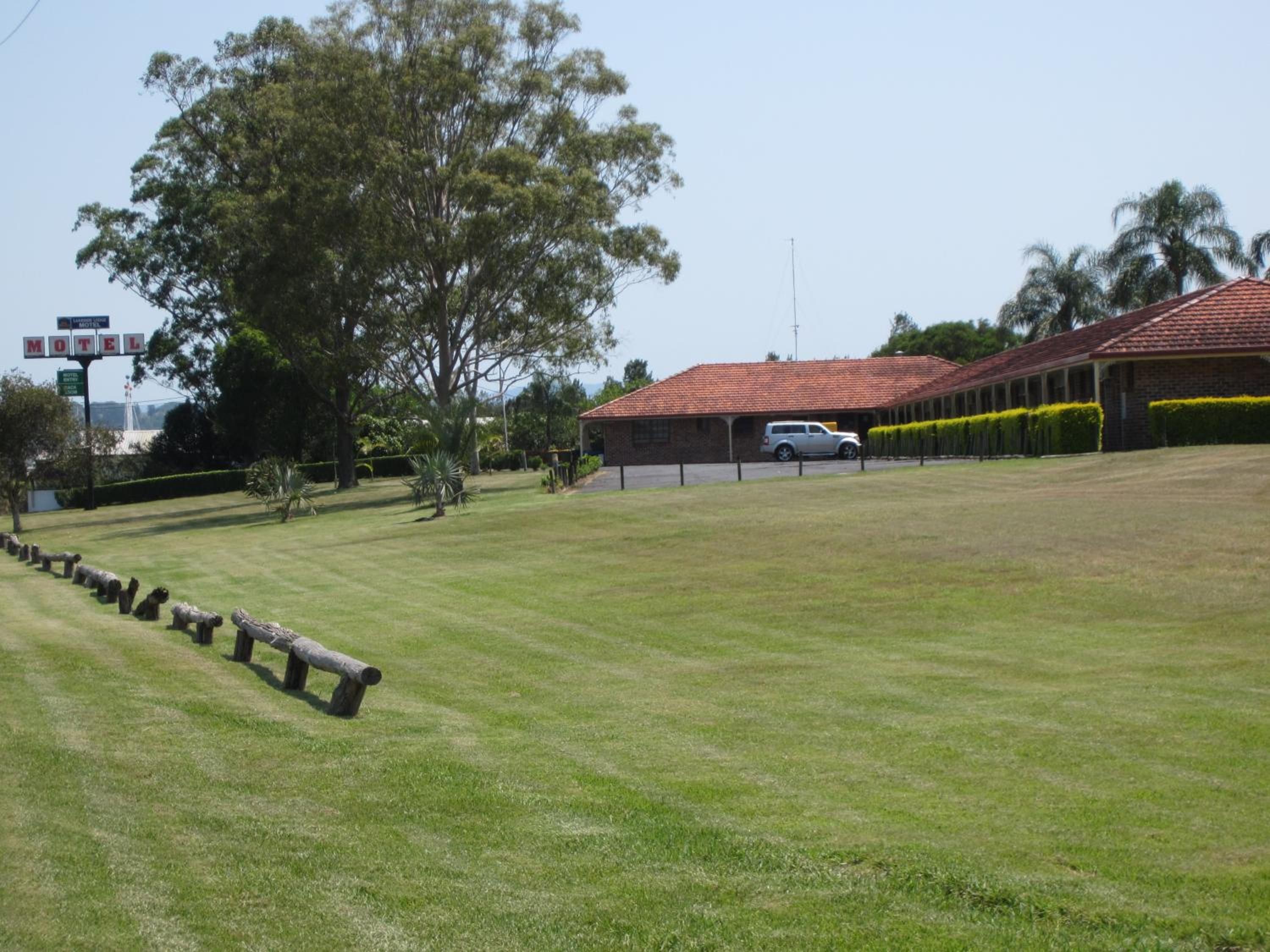 A motel with a red-tiled roof, a parking area, and a grassy lawn.