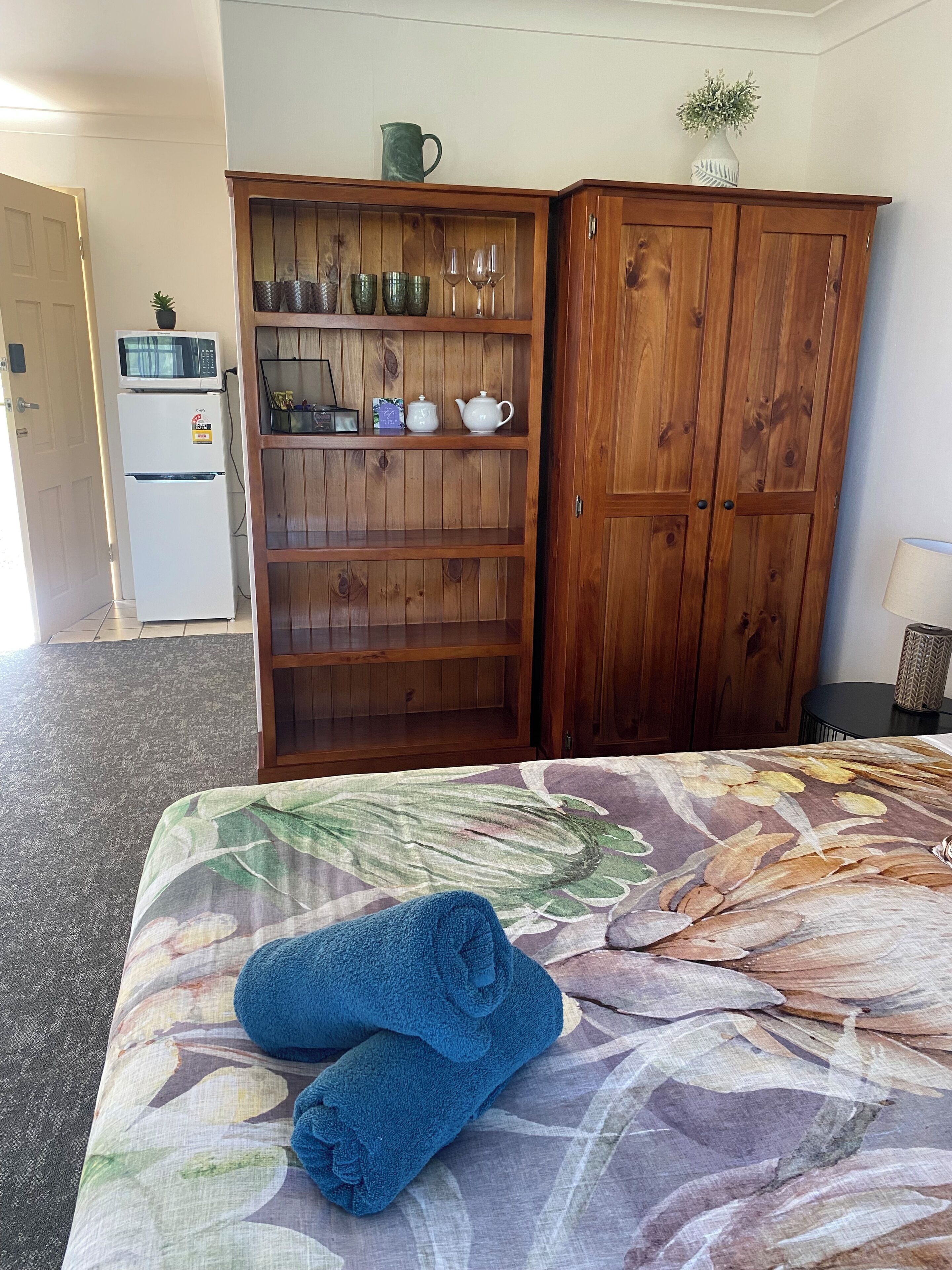 Una habitación de hotel con una cama, un armario de madera, un microondas y un refrigerador.