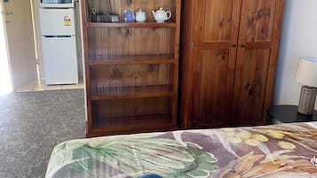 Una habitación de hotel con una cama, un armario de madera, un microondas y un refrigerador.