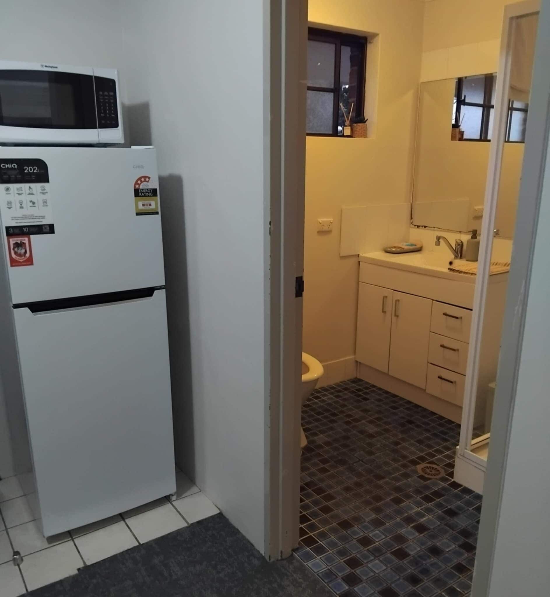 A compact kitchen with a white refrigerator, a microwave, and a sink.