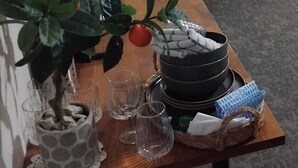 Una mesa de comedor dispuesta con platos, vasos y una planta en maceta.