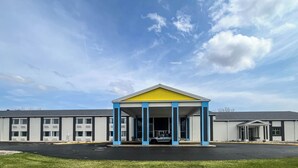 A building with a yellow and blue entrance, a parking lot, and a clear sky.