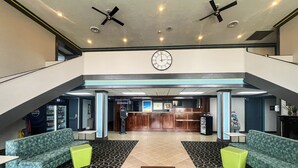 A lobby with a reception desk, seating area, and a clock on the wall.