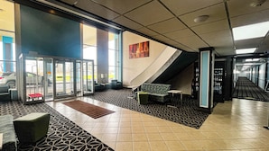 A hotel lobby with a reception desk, seating area, and a staircase leading to upper floors.