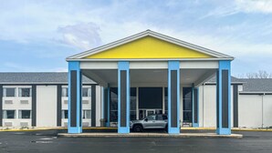 A building with a yellow roof and blue columns, a parked car, and a clear sky.