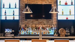 A bar area with shelves of liquor bottles, a television, and two pendant lights. - Doubletree by Hilton Monroe Township Cranbury (Monroe Township)
