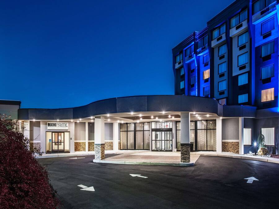 Ein Hotel mit gewölbter Fassade, einem auffälligen Schild mit der Aufschrift "390 PRIME" und einem Parkplatz mit Richtungspfeilen.