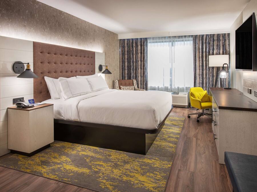 Une chambre d’hôtel moderne équipée d’un grand lit, d’un bureau, d’une chaise et d’une télévision.
