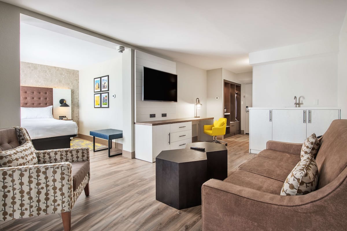Ein modernes Hotelzimmer mit Bett, Sofa, Schreibtisch und Fernseher.