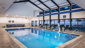 An indoor swimming pool with lounge chairs, a pool lift, and large windows. - Doubletree by Hilton Monroe Township Cranbury (Monroe Township)