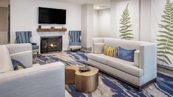 A modern living room with a fireplace, sofas, armchairs, and a television.