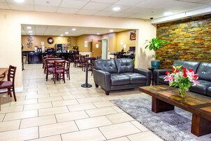 A spacious lobby with a dining area, a reception desk, and a seating area with a sofa and coffee table.