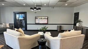 A lobby with two beige sofas, a black coffee table, and a television on the wall.