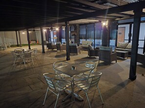 An outdoor patio area with metal tables and chairs, wicker sofas, and a stone fireplace. - Abilene Whitten Inn (Abilene)