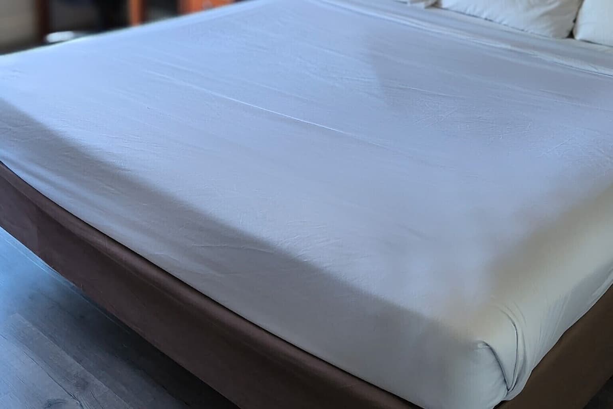 A neatly made bed with white linens in a hotel room.