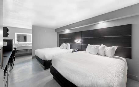 A modern hotel room with two beds, a large mirror, and a desk with a chair.