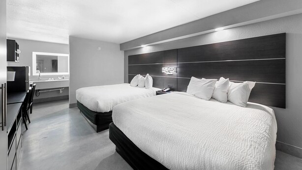 Ein modernes Hotelzimmer mit zwei Betten, einem großen Spiegel und einem Schreibtisch mit Stuhl.