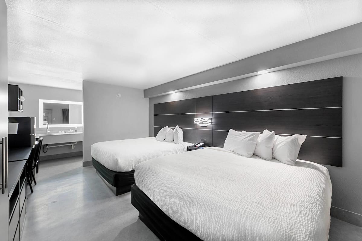 Una habitación de hotel moderna con dos camas, un espejo grande y un escritorio con una silla.