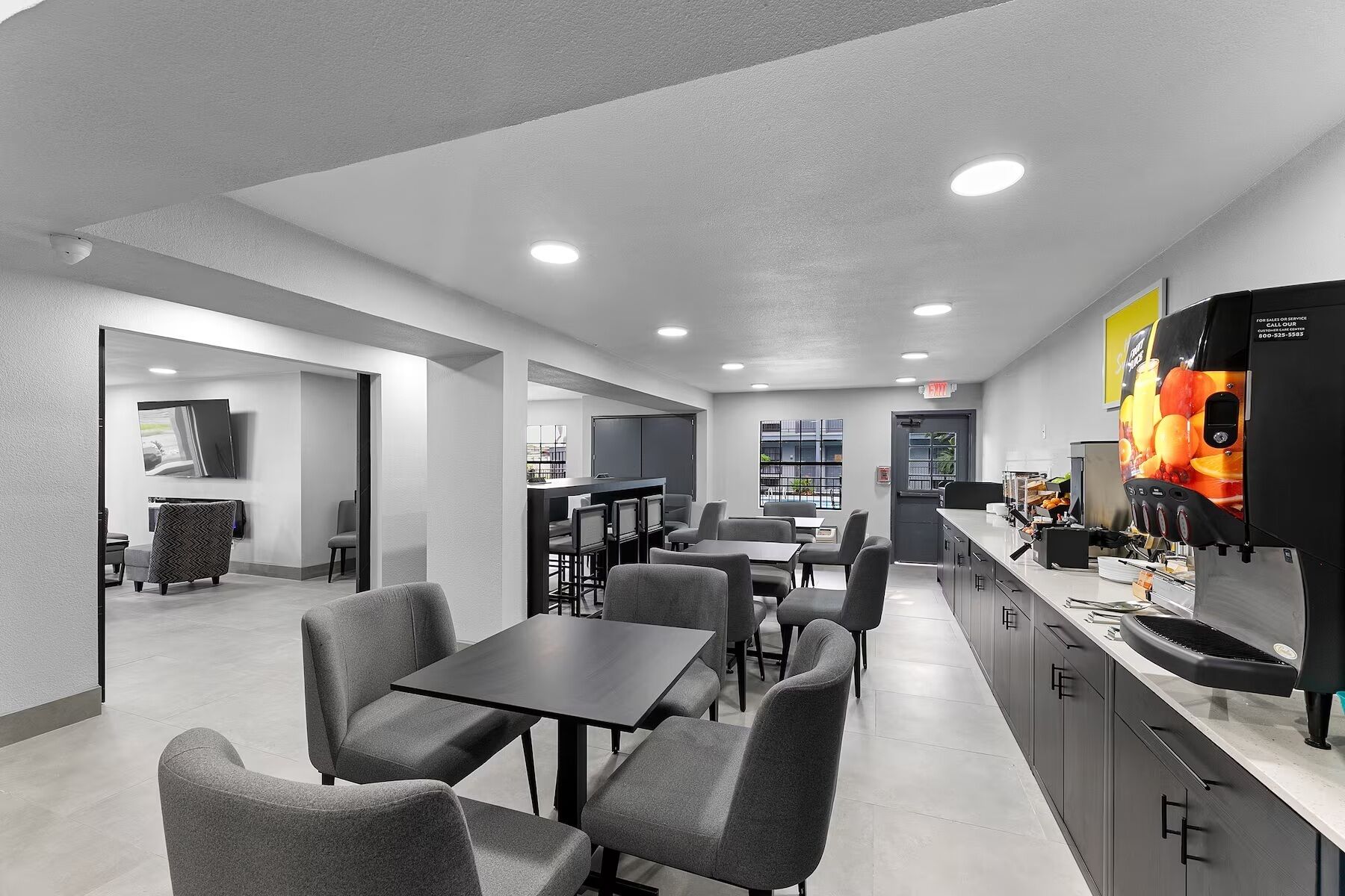 A modern restaurant with a bar area, seating arrangements, and a visible exit sign.
