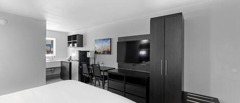 Una habitación de hotel moderna con una cama grande, un escritorio con silla, un televisor y un armario.