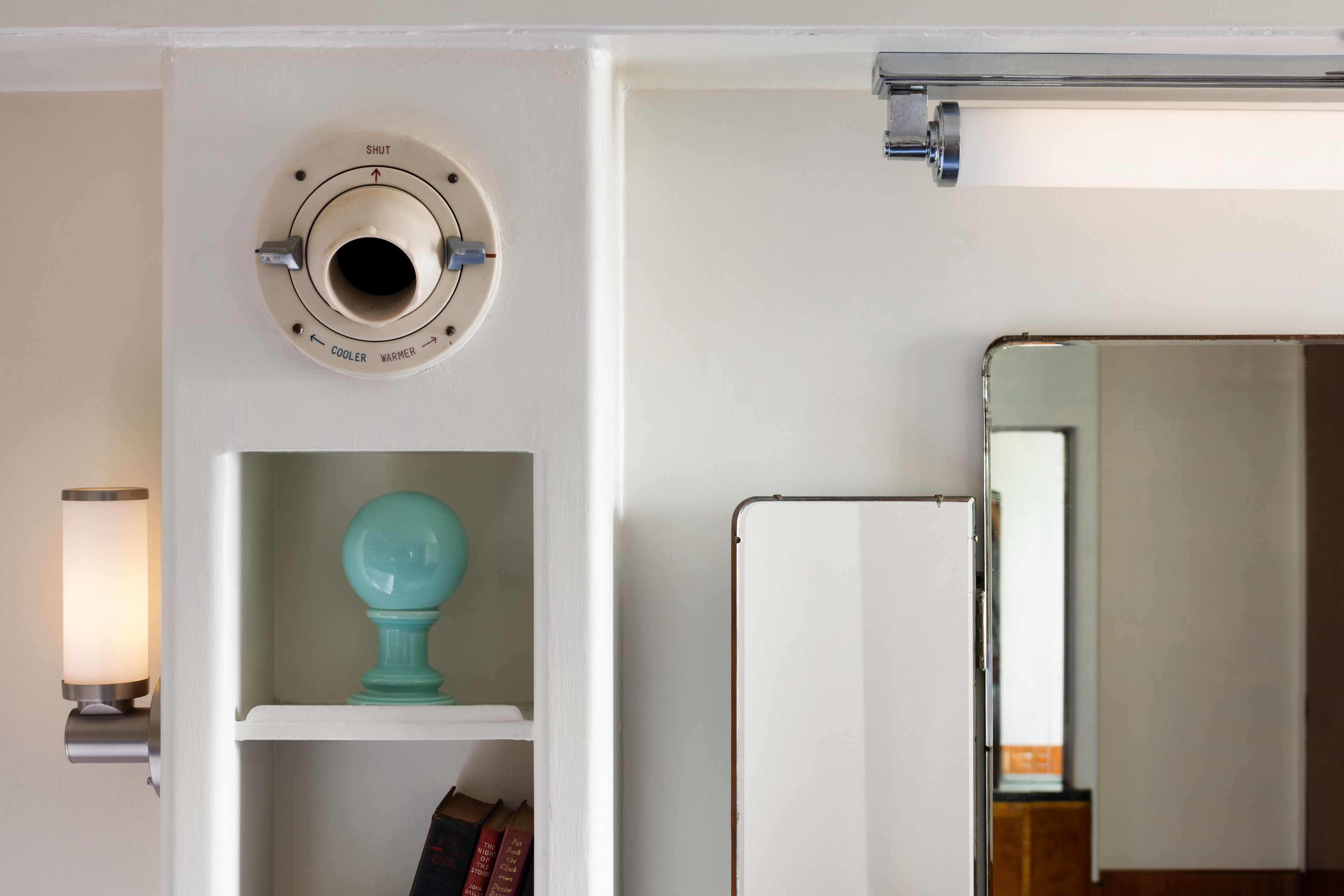 A white wall with a thermostat, a teal decorative item, and a whiteboard.
