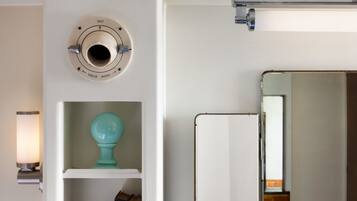 A white wall with a thermostat, a teal decorative item, and a whiteboard.