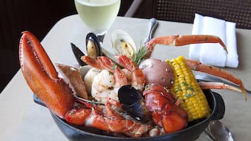 A seafood dish with lobster, mussels, shrimp, and corn on a table.