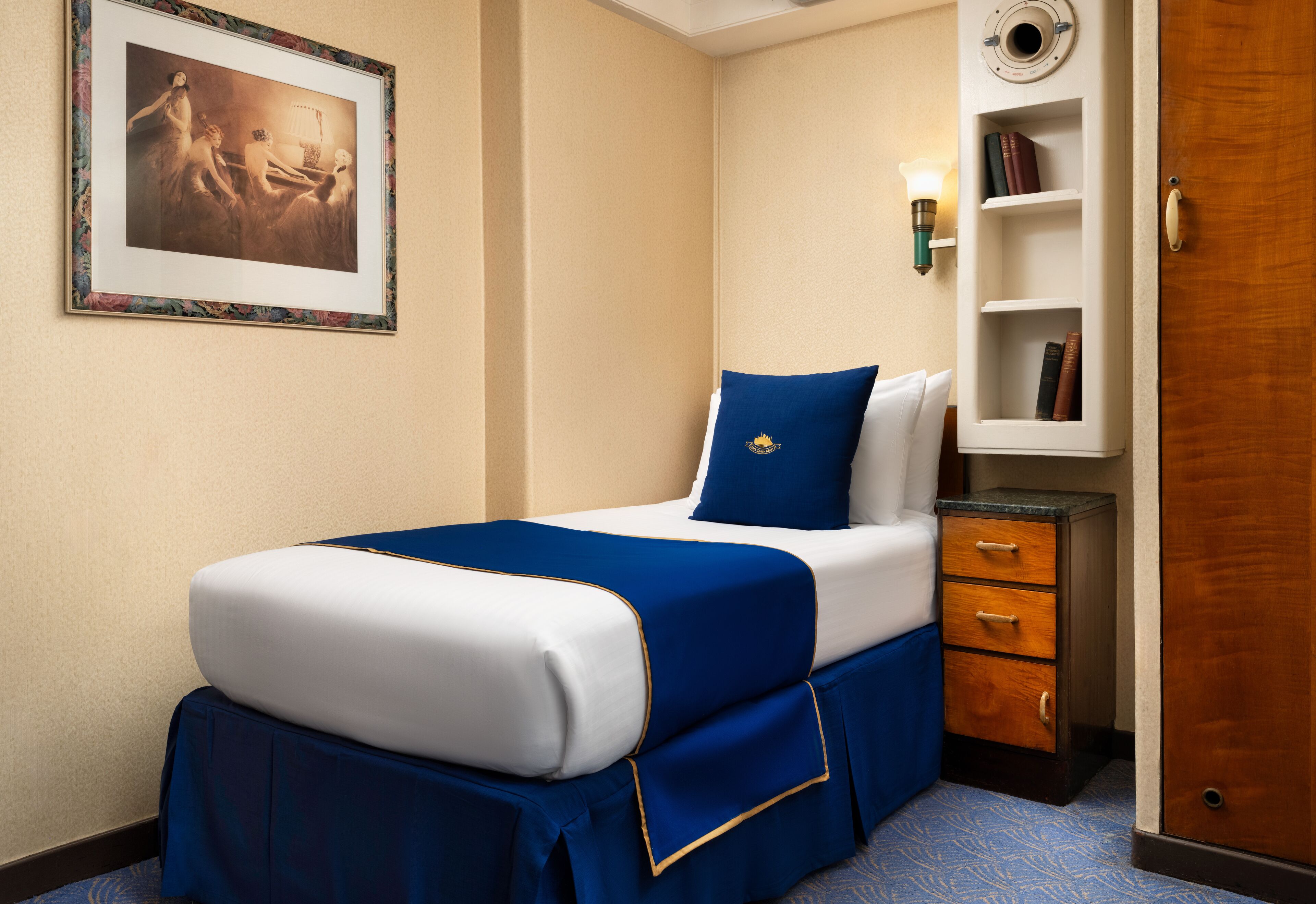 Habitación de hotel con una cama, una mesita de noche, una estantería y una puerta.