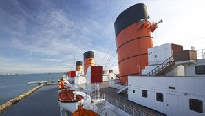 Cubierta de un crucero con botes salvavidas, una gran chimenea y cielo despejado.