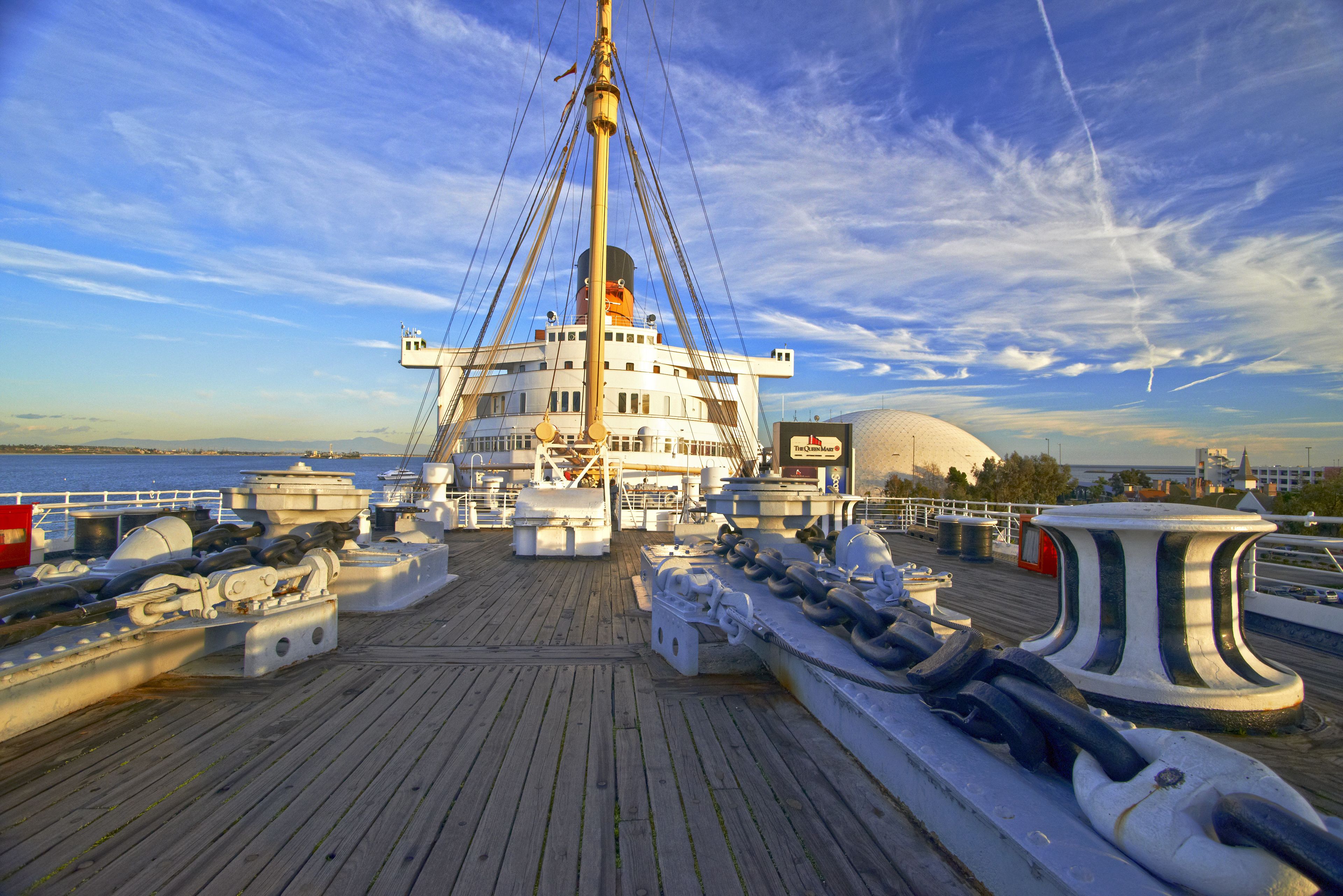 A wooden deck with lifeboats and a mast on a ship.