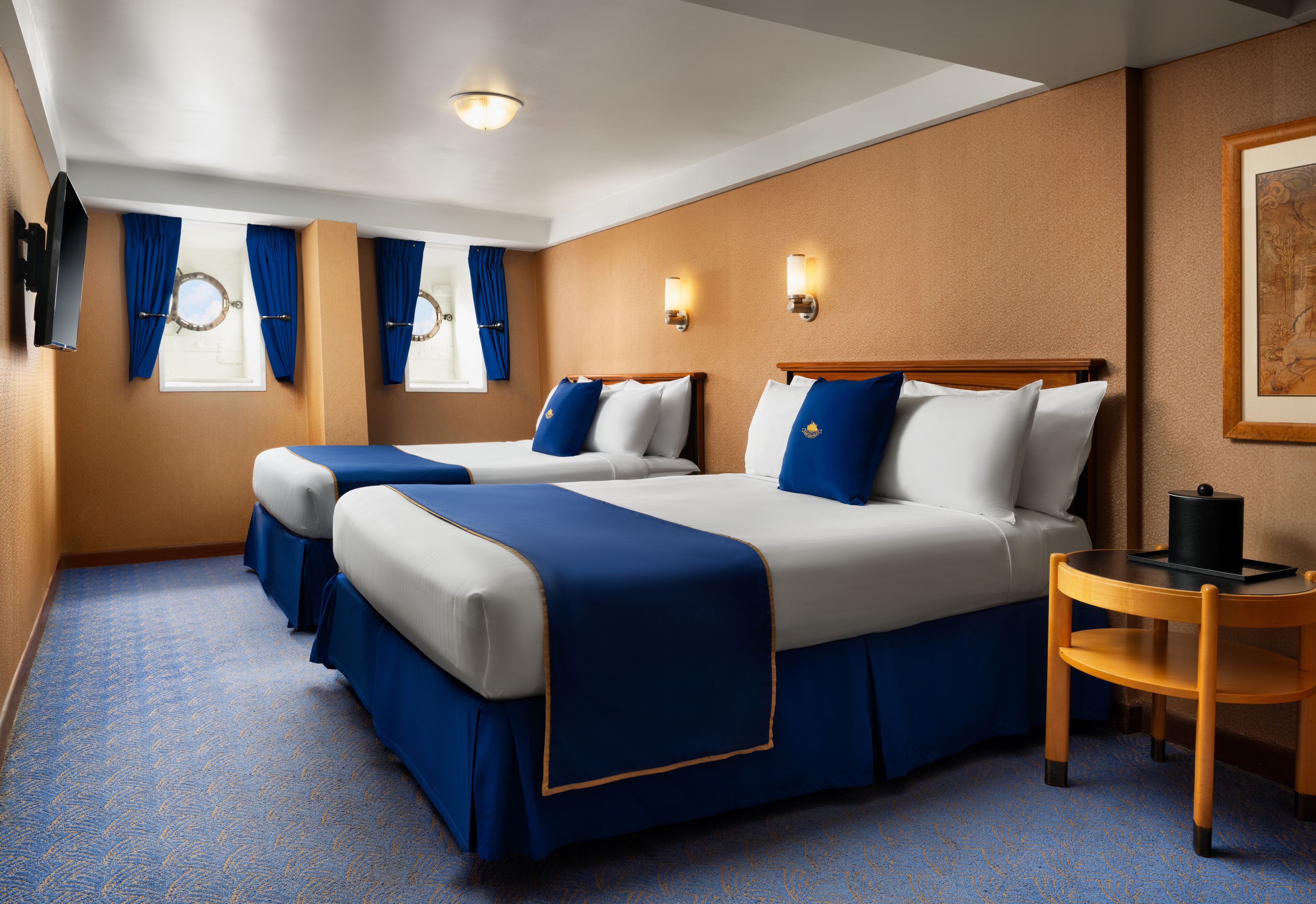 A hotel room with two beds, a small table, and a TV.