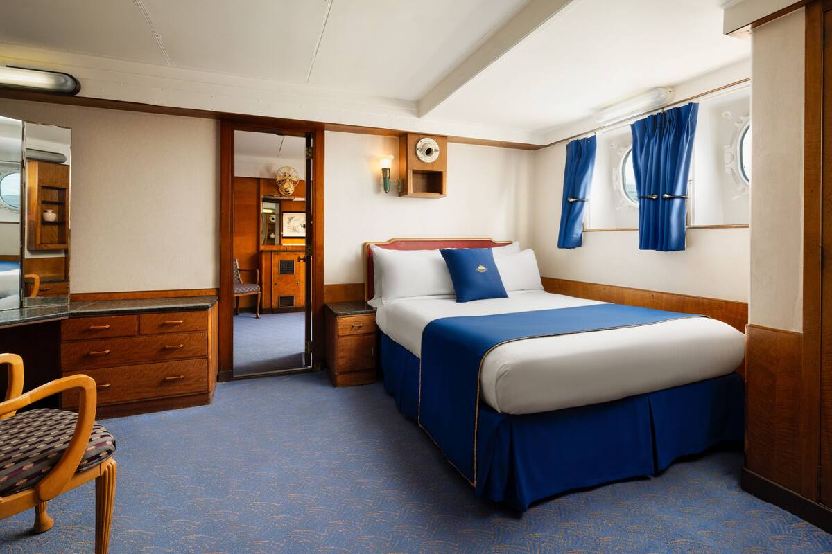 Una habitación de hotel con cama, escritorio, silla y armario.