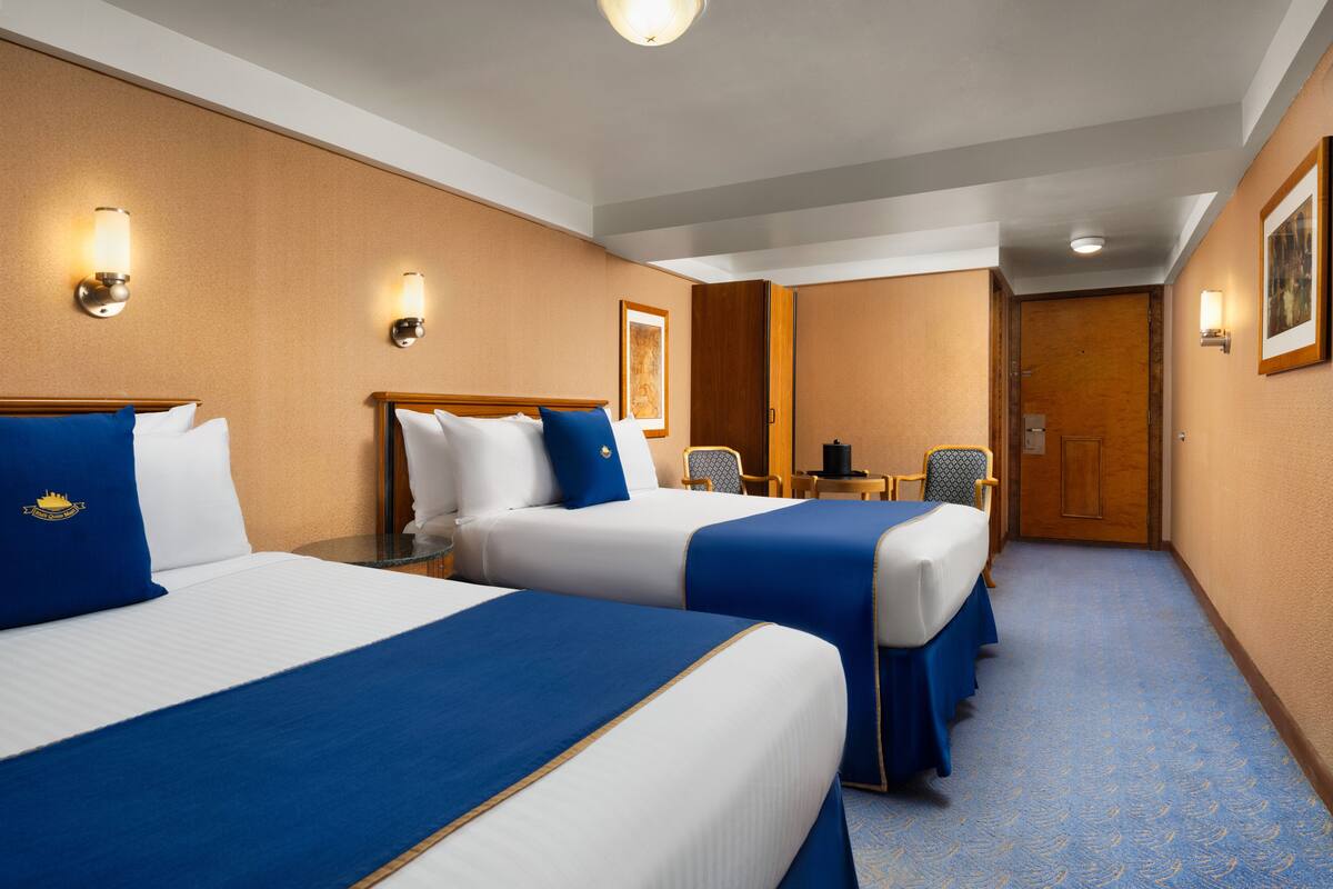 Habitación de hotel con dos camas, un escritorio y una silla.