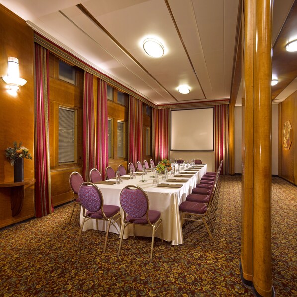 A conference room with a long table, chairs, and a projector screen.